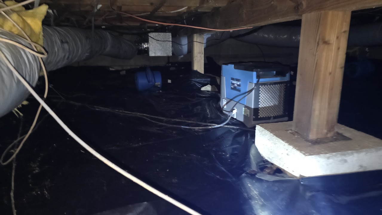 Drying equipment beside a crawlspace support post.